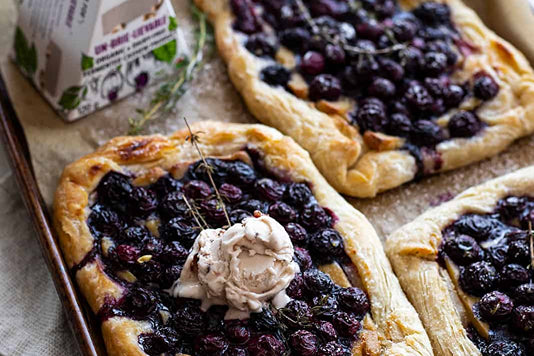 Three prepared pastries stuffed with blueberries and topped with dairy free brie cheese