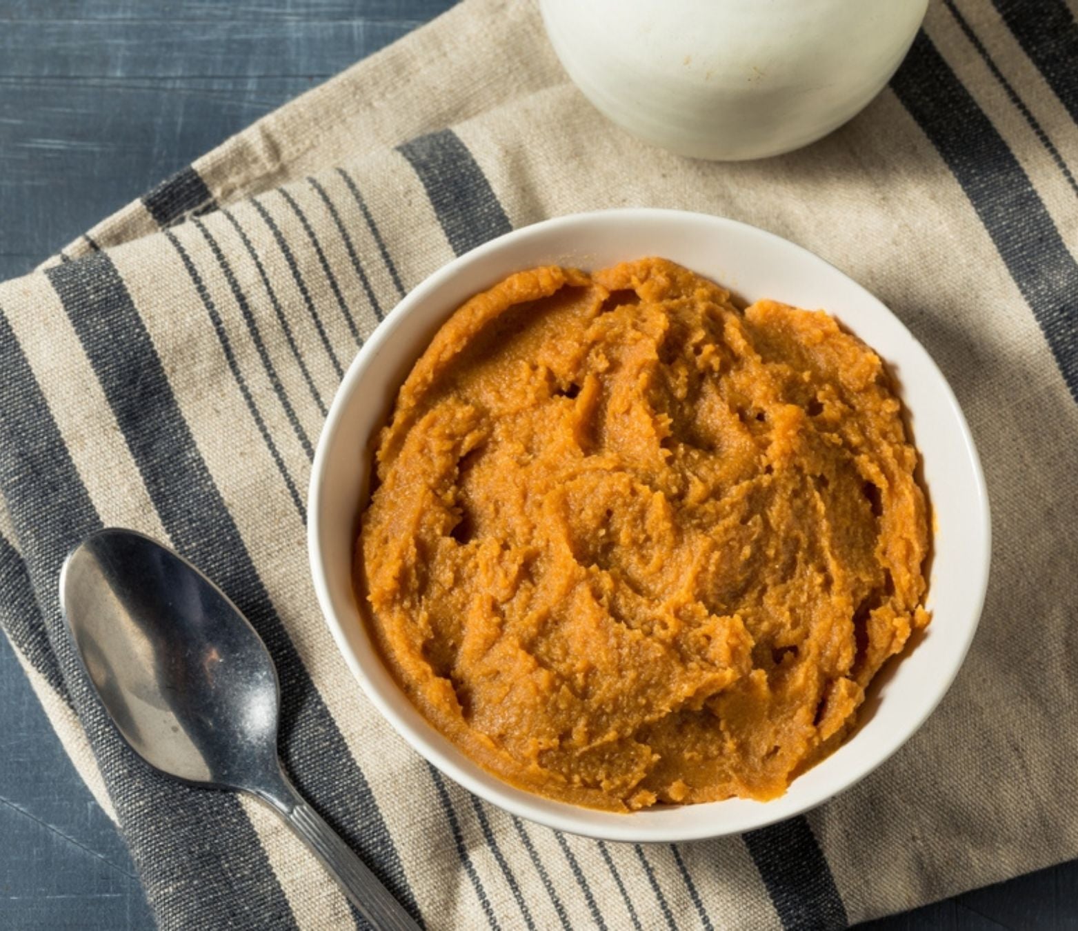 chickpea miso in a white bowl on a blue and beige towel with a metal spoon