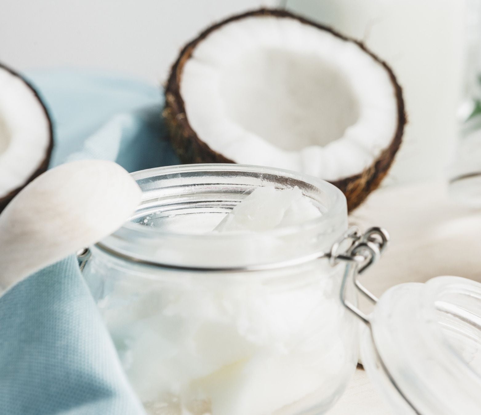 coconut shavings inside a clear jar with coconuts in the background