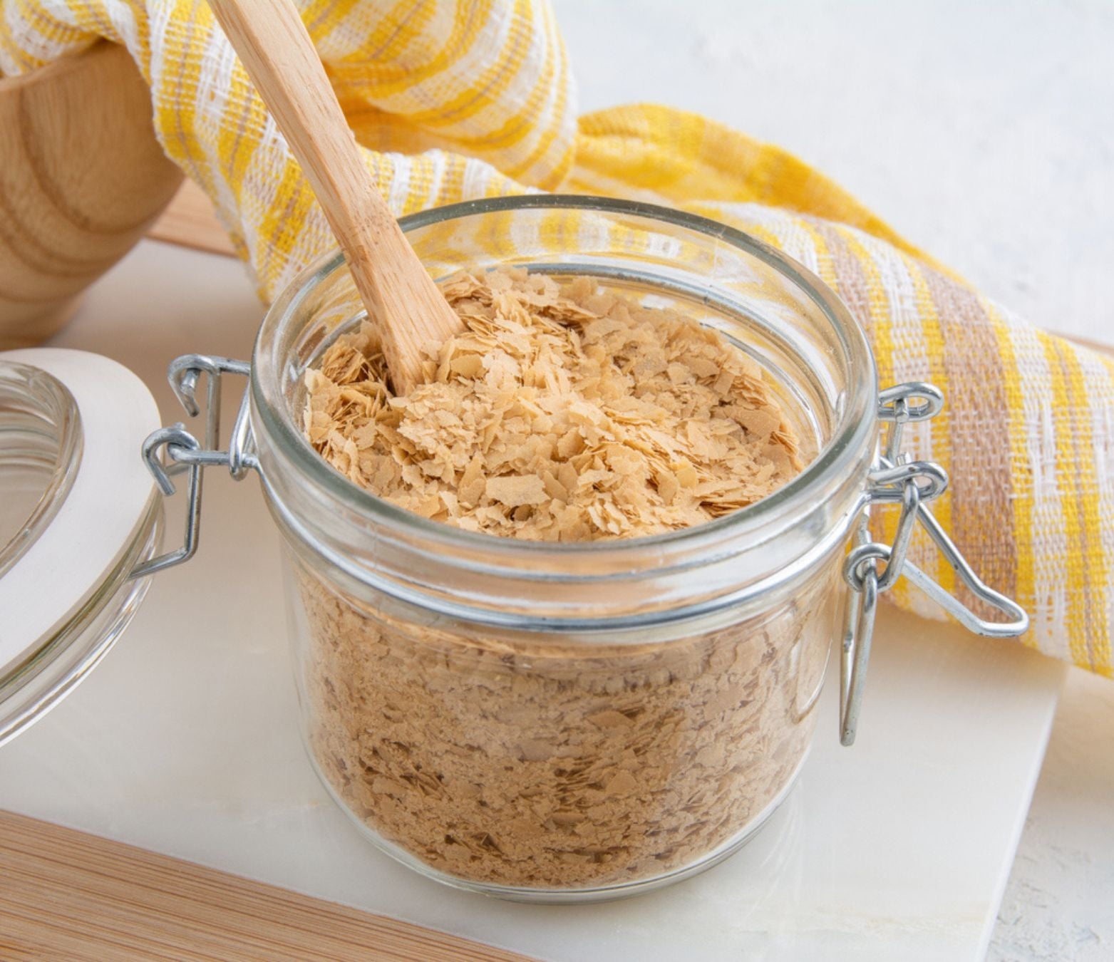 nutritional yeast in a clear glass jar with a yellow cloth in the background