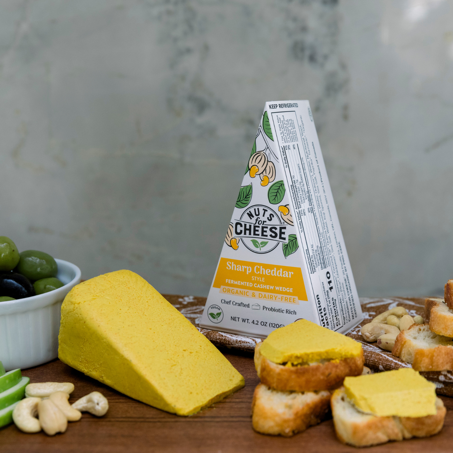 Nuts For Cheese Quartiers de cheddar fort sur une planche de bois avec du pain.