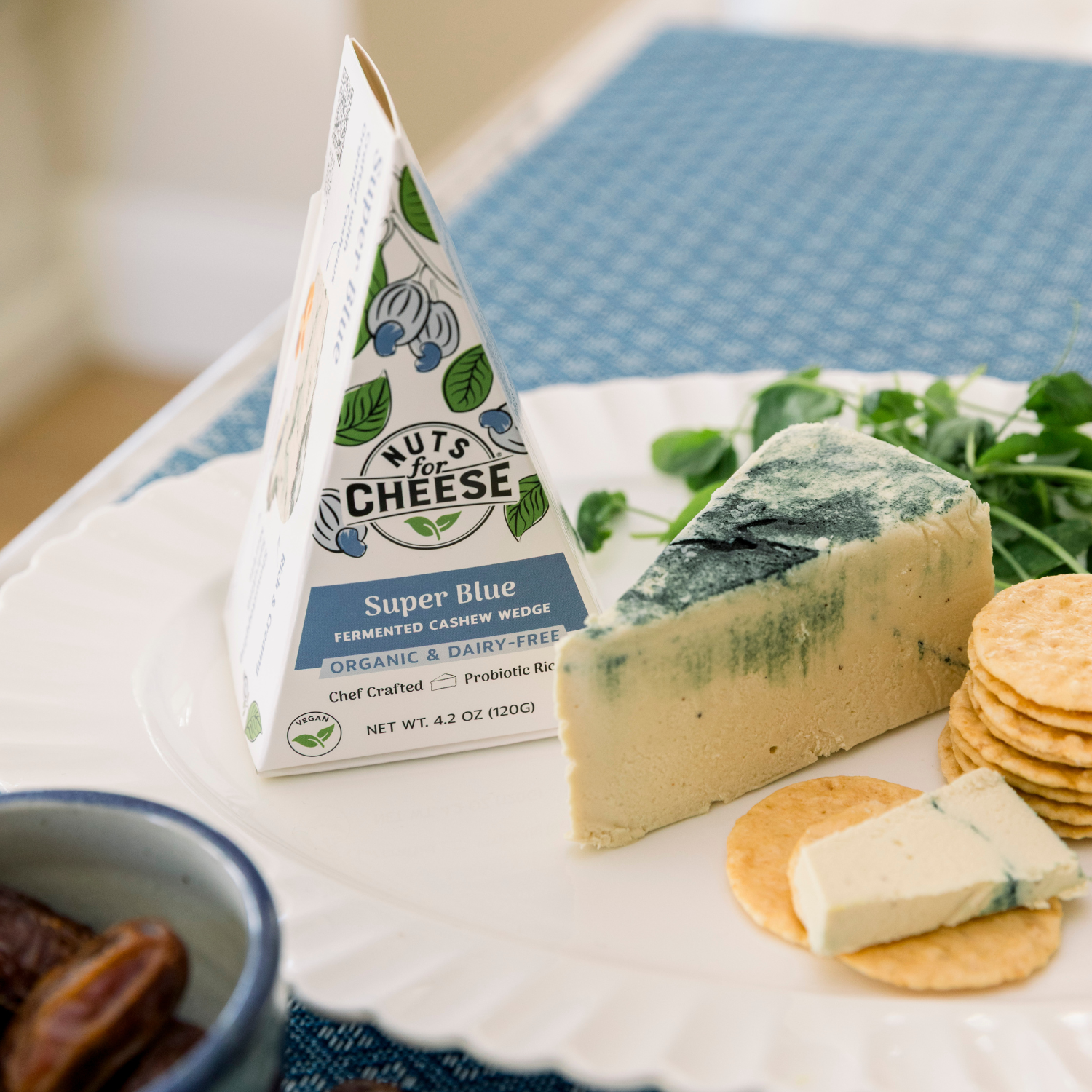 Nuts for Cheese Coin de noix de cajou Super Blue avec des crackers sur une assiette.