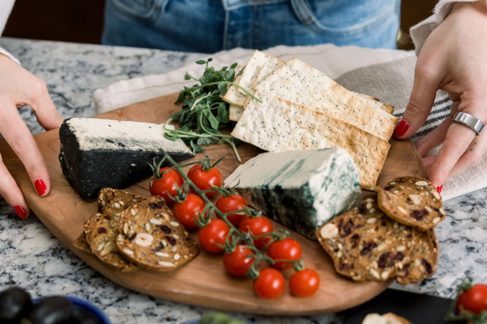 Nuts For Cheese dairy free cheese wedges beautifully displayed on a cheeseboard with crackers and fresh vegetables.