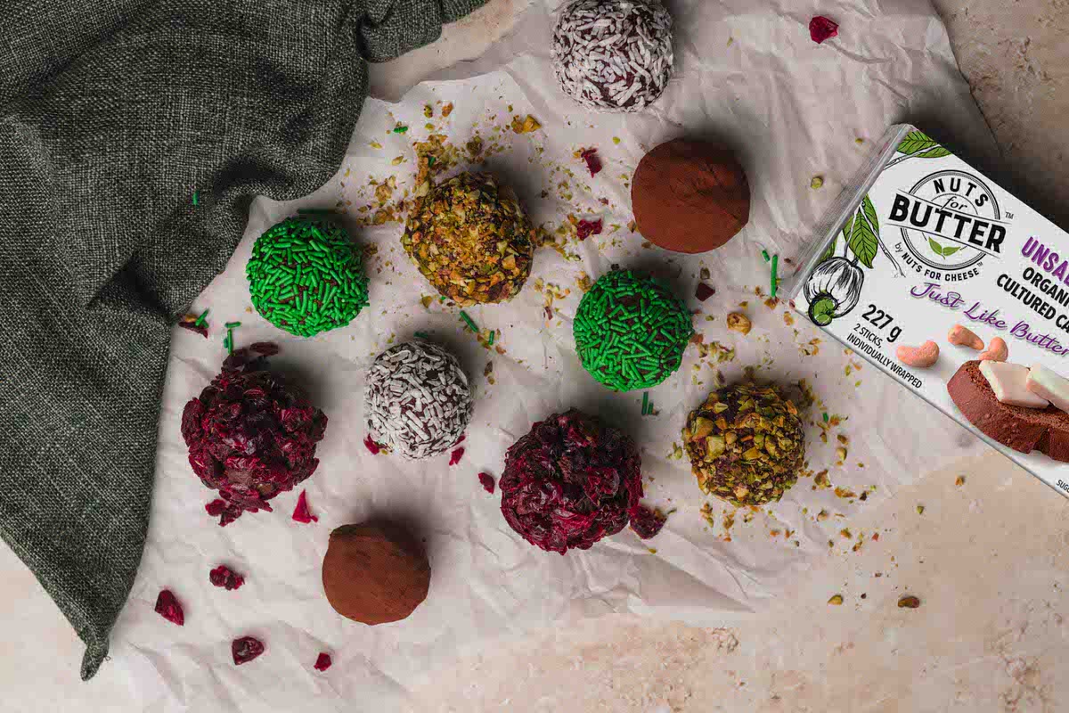 Dairy-Free vegan chocolate truffles in assorted colours sitting on parchment paper next to a box of dairy-free butter.