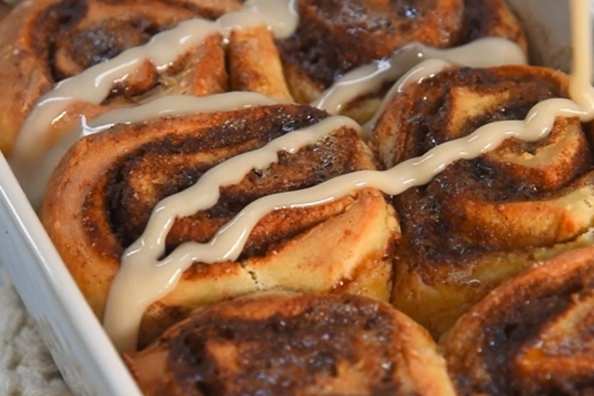 Baked vegan cinnamon rolls drizzled with a dairy-free cream dressing.
