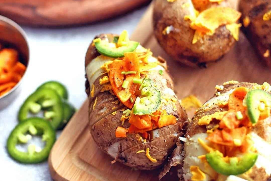 Baked potatoes stuffed with dairy-free chipotle cheddar cheese and topped with coconut bacon and jalapenos.