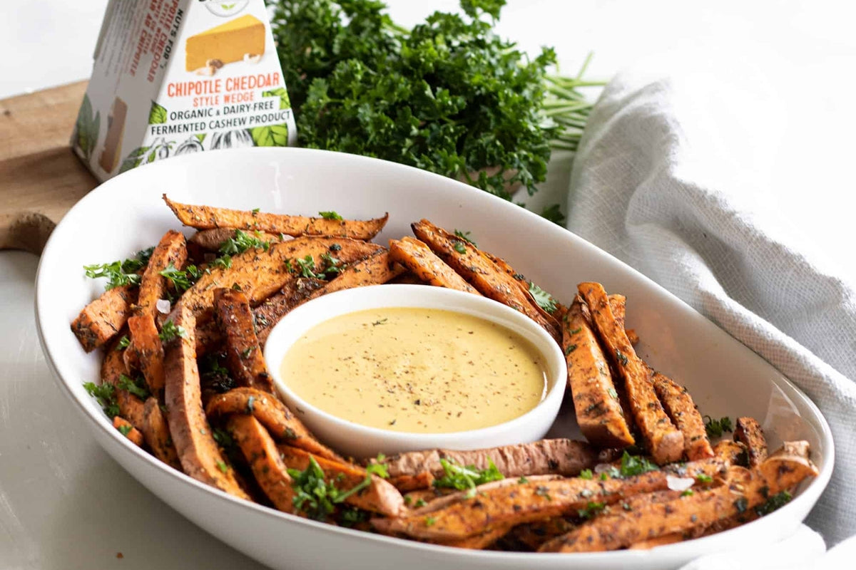 A bowl of sweet potato fries surrounding a dipping sauce made with dairy free chipotle cheddar cheese.