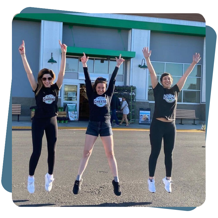 Nuts For Cheese team jumping with arms in the air outside a Sprouts Farmers Market store.