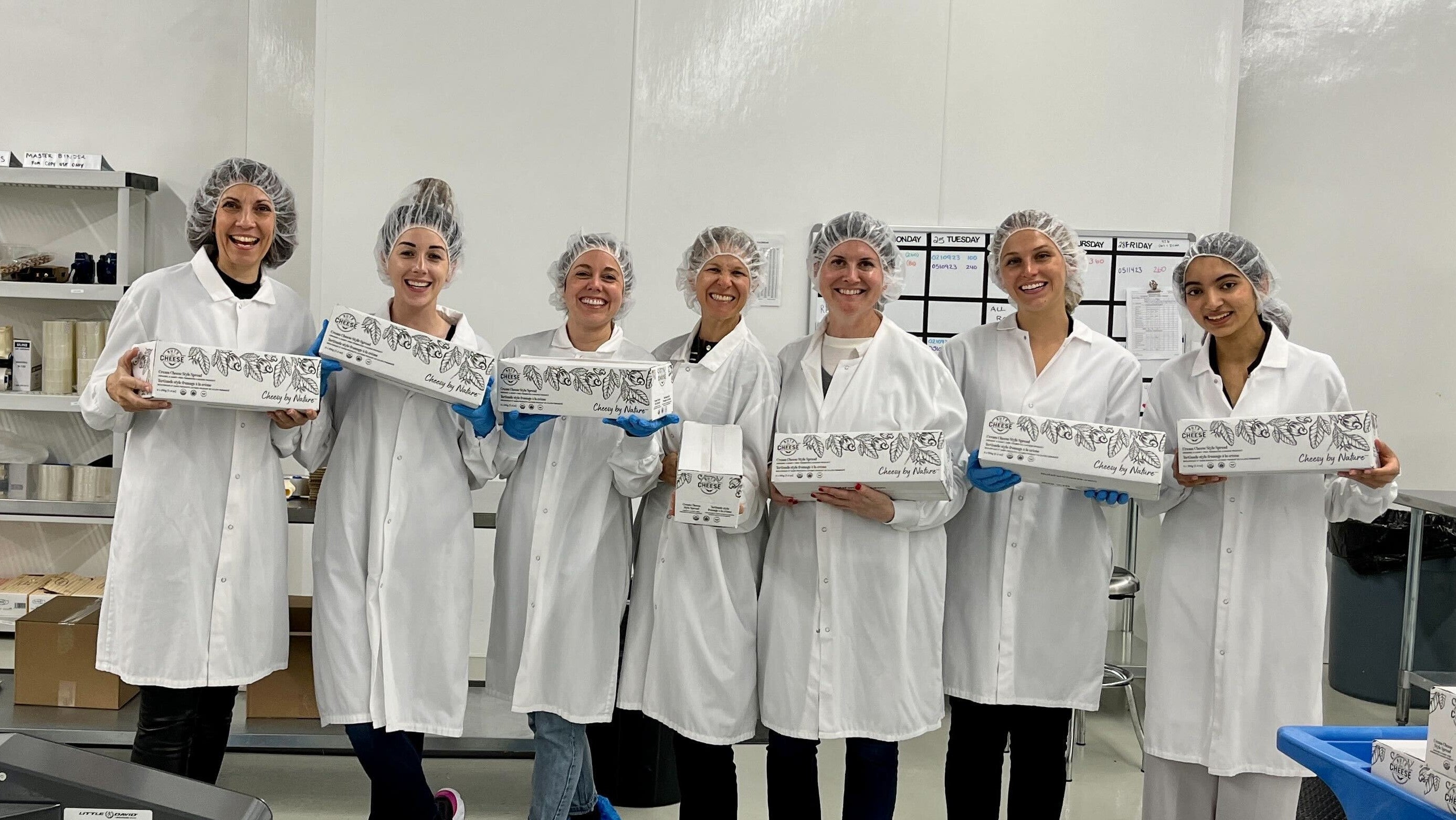 Nuts For Cheese team members in the manufacturing facility holding boxes of dairy-free cheese