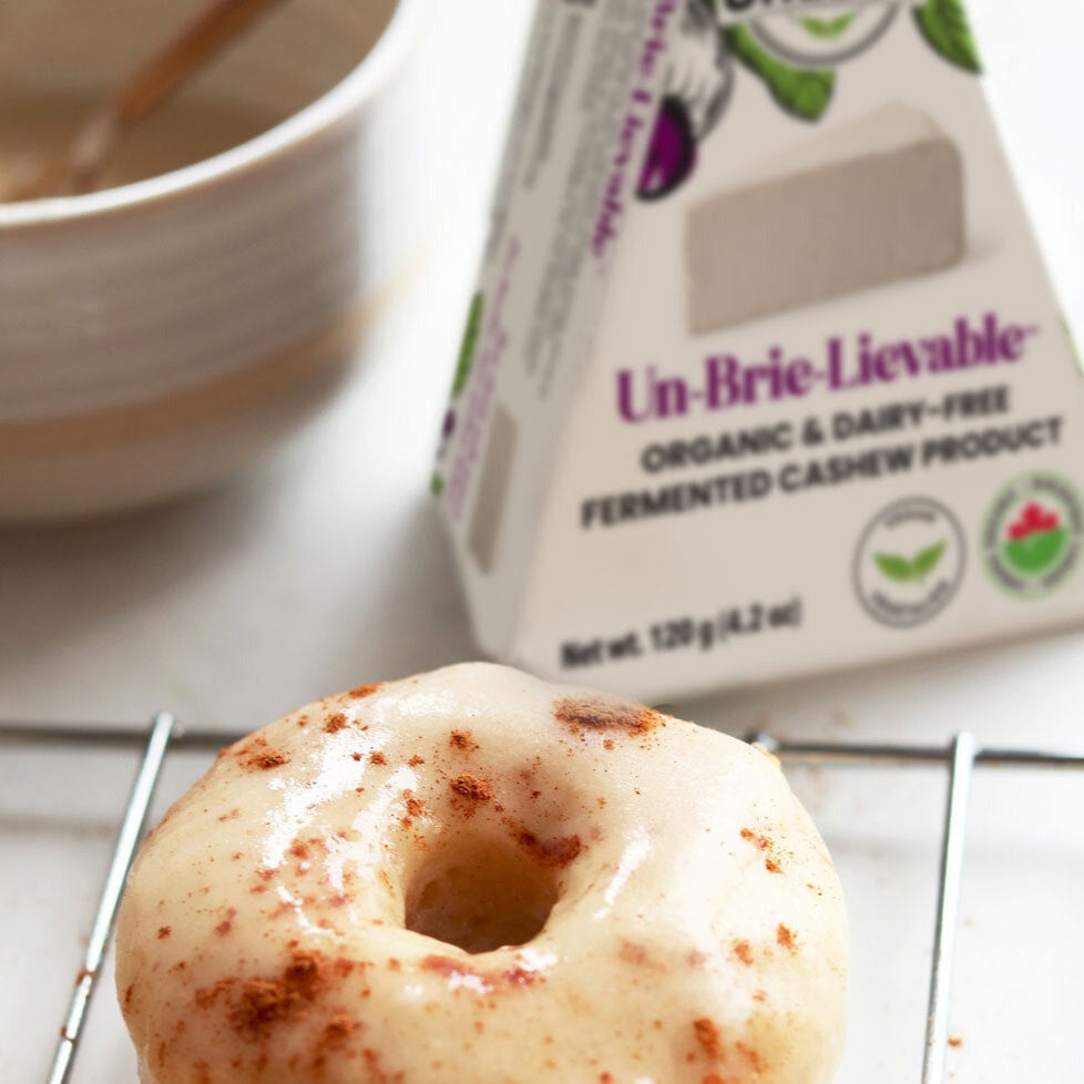 plant-based brie cheese cinnamon glazed vegan donuts with a Nuts For Cheese™ Organic & dairy-free fermented Un-Brie-Lievable™ Brie cheese wedge package